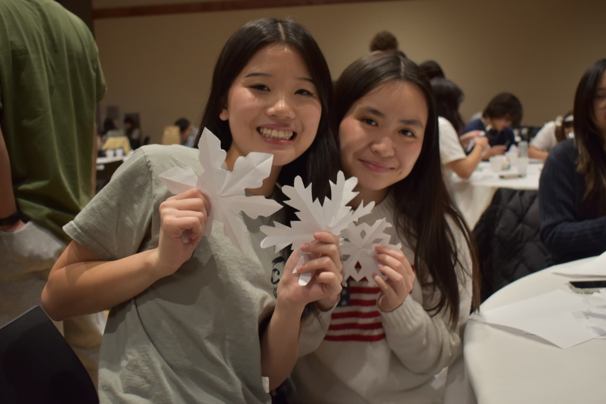 Two SASE members holding paper snowflakes they made at a winter event